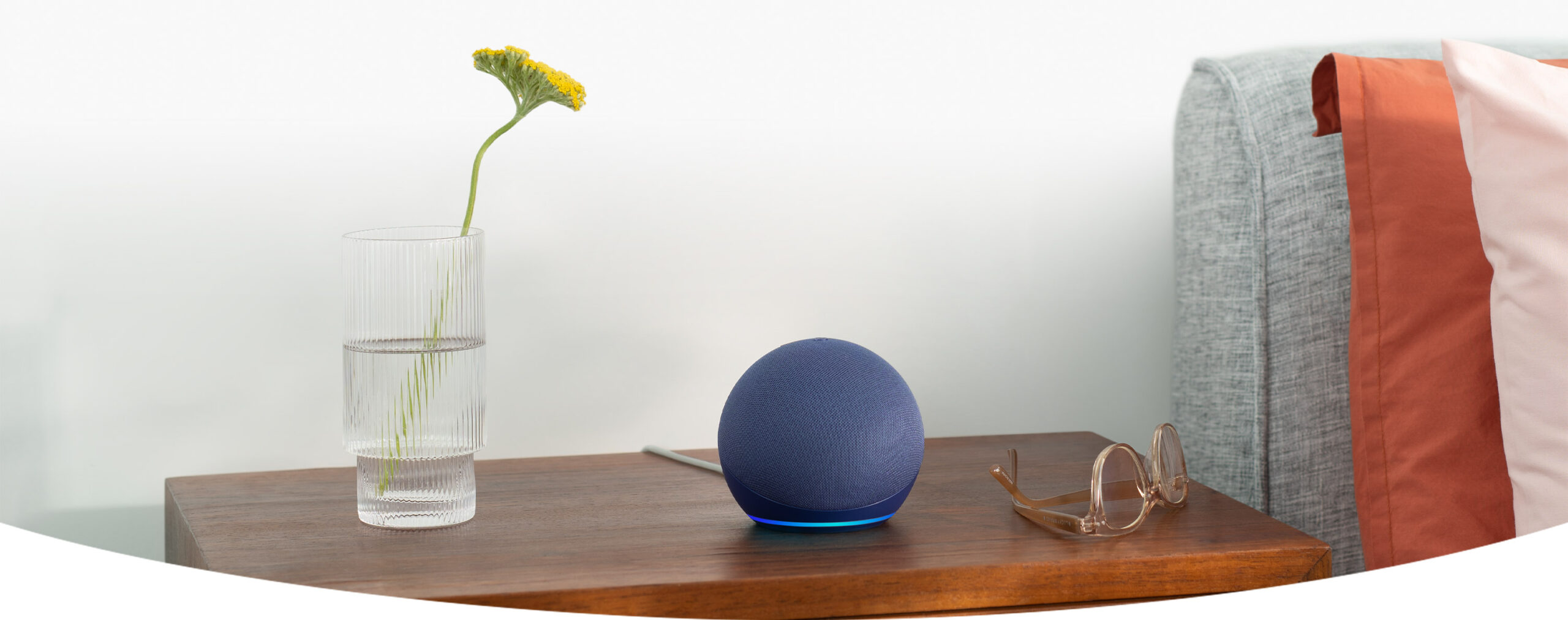 Echo Dot en mesa de noche junto a un florero